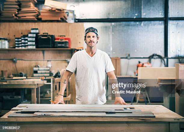 portrait of confident carpenter standing at workbench in workshop - workbench stock pictures, royalty-free photos & images