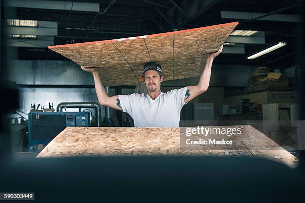 carpenter carrying wooden plank on head at workshop - carrying on head stock pictures, royalty-free photos & images