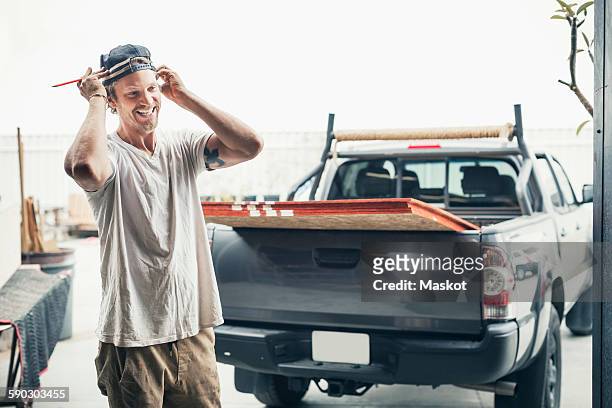 happy carpenter standing by pick-up truck outside workshop - designer einrichtung stock-fotos und bilder