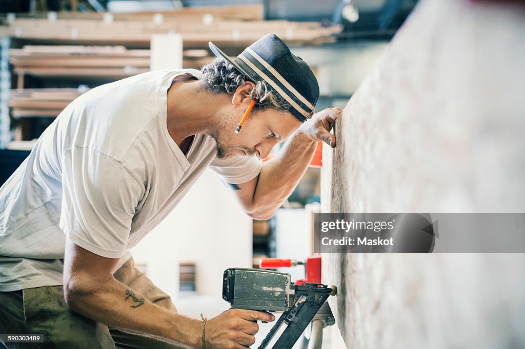 Side view of carpenter working on wooden plank at workshop