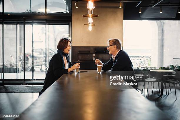 side view of senior couple talking while having coffee at cafeteria - coffee shop chat imagens e fotografias de stock