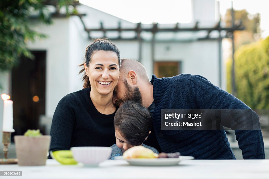 Portrait of happy woman sitting with family at yard