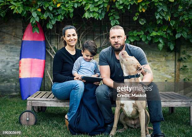 portrait of family sitting with dog at yard - mann frau hund zuhause stock-fotos und bilder