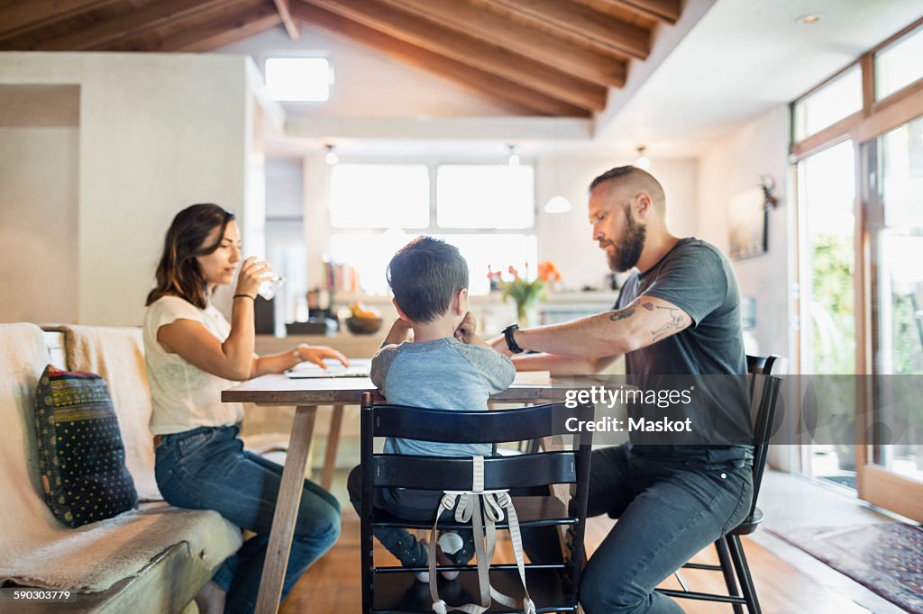 Family of three sitting at dining table in house