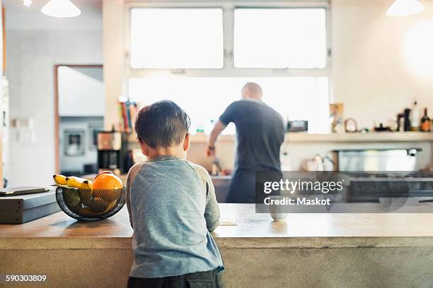 rear view of father and son in kitchen - fruitschaal stockfoto's en -beelden