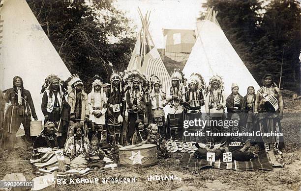 Real photo postcard features a group of Natives, in full parade dress, posing at an encampment, Oregon, circa 1910.