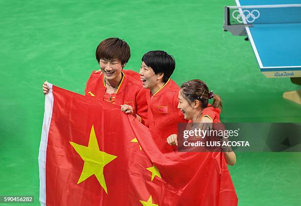 China's Ding Ning , Li Xiaoxia and Liu Shiwen carry the national Chinese flag as they celebrate winning the women's team gold medal final table...