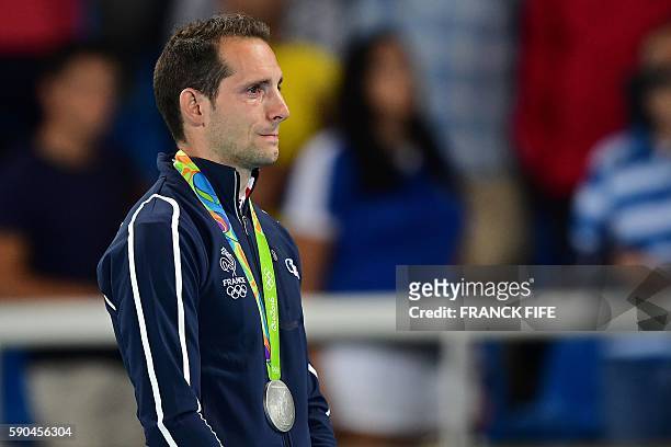 Silver medallist France's Renaud Lavillenie cries on the podium during the medal ceremony for the men's pole vault during the athletics event at the...