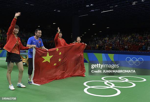 China's Ding Ning, coach Kong Linghui, Li Xiaoxia and Liu Shiwen pose with the national Chinese flag after winning gold medals in the women's team...