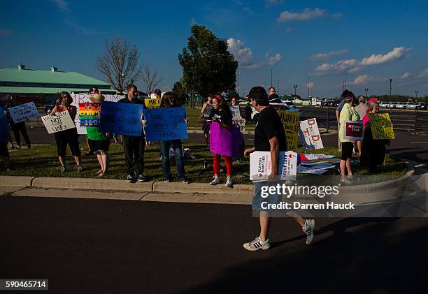 Trump supporter walks past a row of protestors before Republican presidential nominee Donald Trump speaks at a rally on August 16, 2016 in West Bend,...