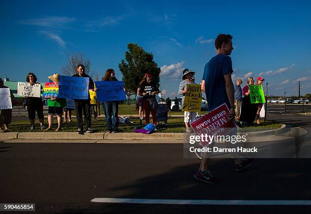 Trump supporter walks past a row of protestors before Republican presidential nominee Donald Trump speaks at a rally on August 16, 2016 in West Bend,...