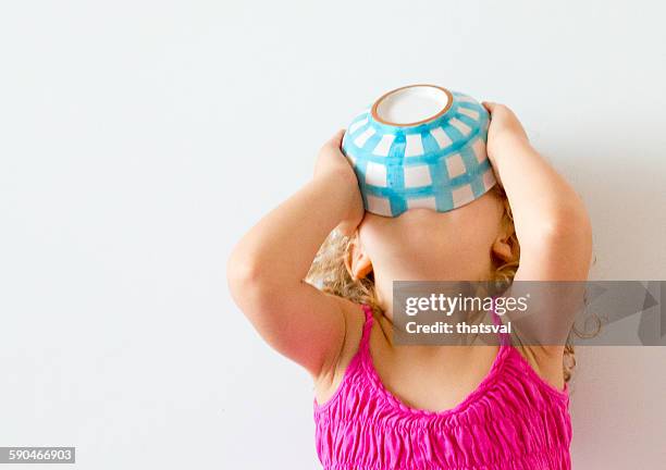 girl with head back holding cereal bowl to her mouth - avoir faim photos et images de collection