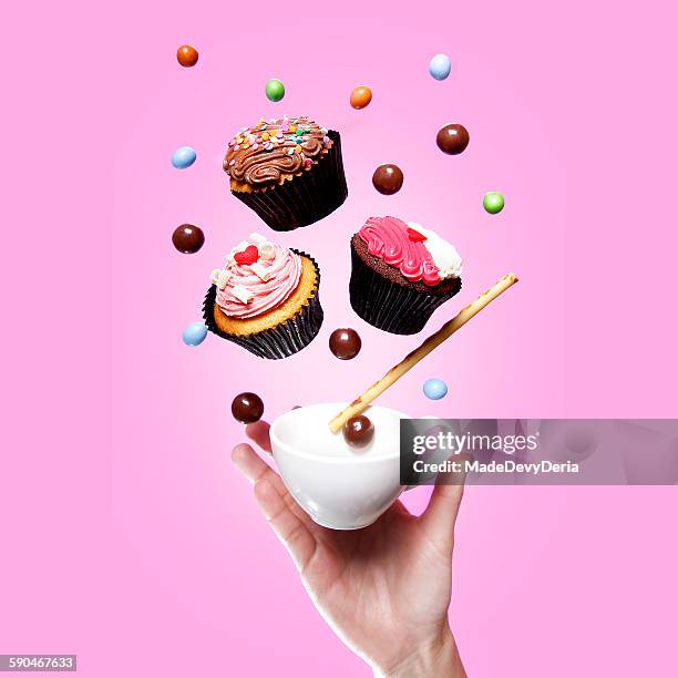 flying cupcakes, teacup, sweets and a hand - cupcake teacup stock-fotos und bilder