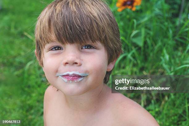 portrait of a smiling boy with a milk moustache - milk moustache stock-fotos und bilder