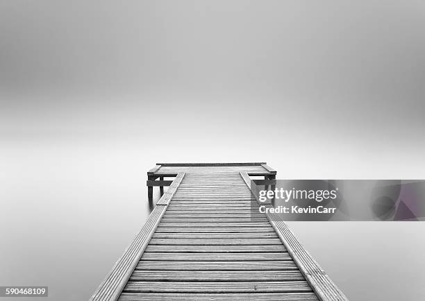 empty wooden jetty in the mist - grey pier stockfoto's en -beelden