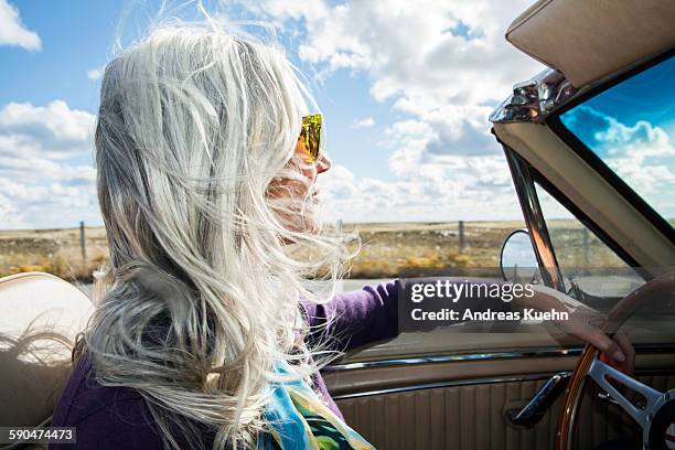 woman driving a convertible on a sunny day. - white hair stock-fotos und bilder