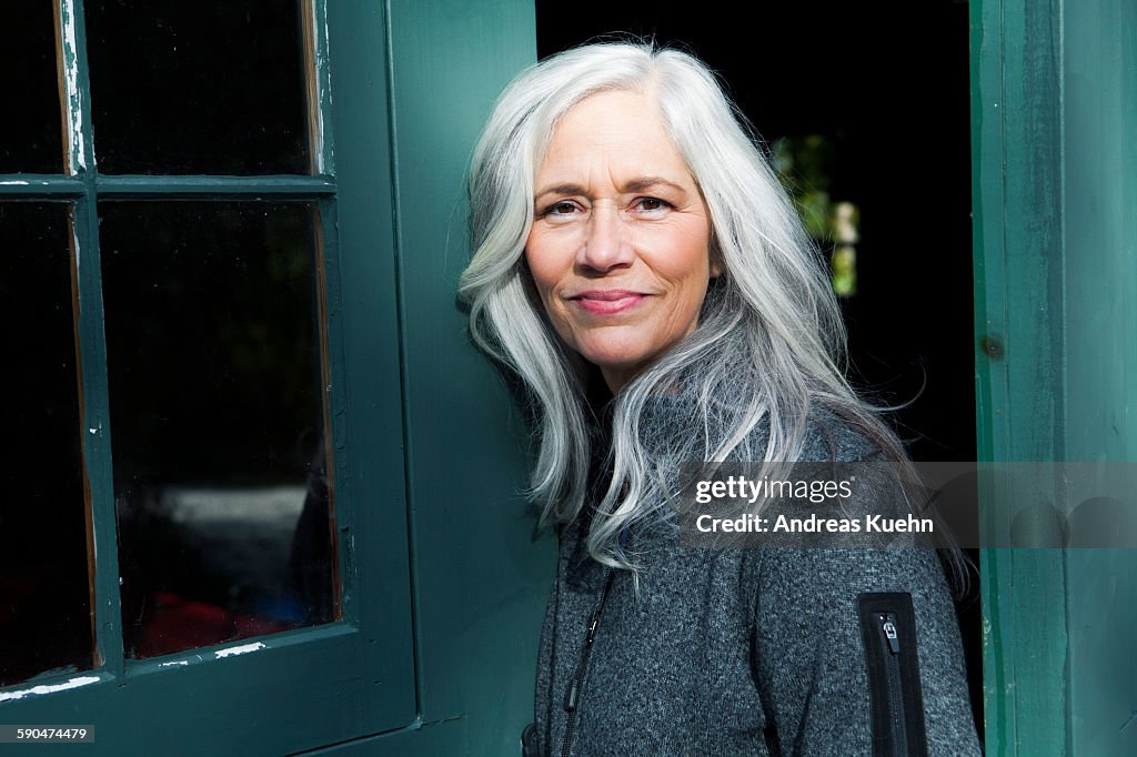 Woman with light, gray hair outside smiling.