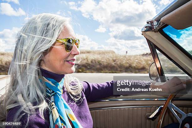 woman in a car with her hair blowing in the wind. - baby boomer stock pictures, royalty-free photos & images
