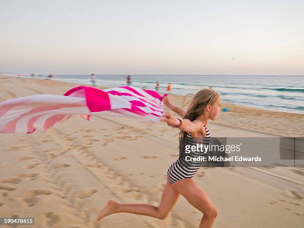 young girl wth striped towel on beach - girl blowing sand stock-fotos und bilder