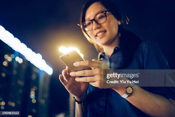 young woman using smartphone in city at night - yiu yu hoi stock pictures, royalty-free photos & images