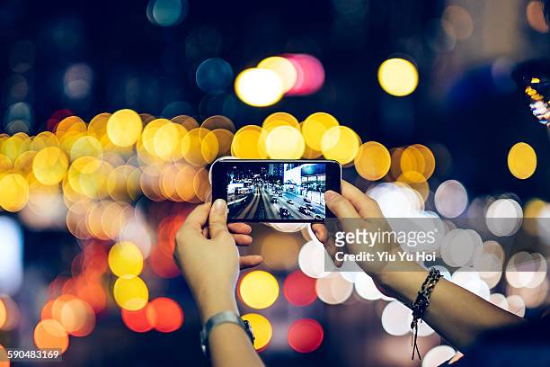 woman photographing night scene with smartphone - yiu yu hoi stock pictures, royalty-free photos & images
