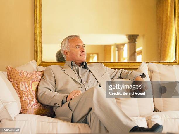 older man sitting on couch - gold suit ストックフォトと画像