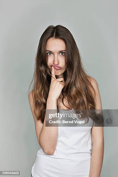 studio portrait of young woman - finger on lips stock-fotos und bilder