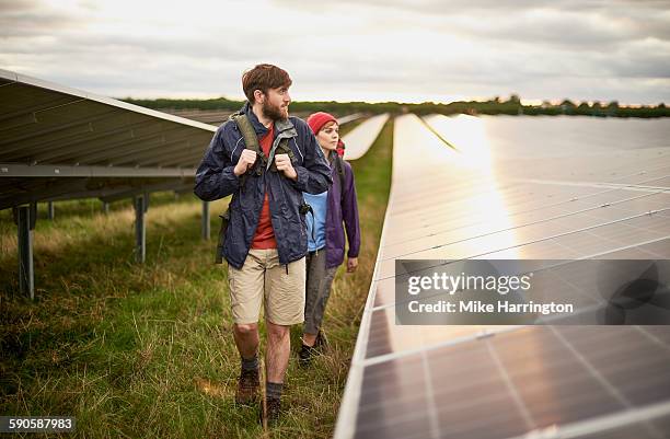 young couple hiking through solar farm - solar panel array front view stock pictures, royalty-free photos & images