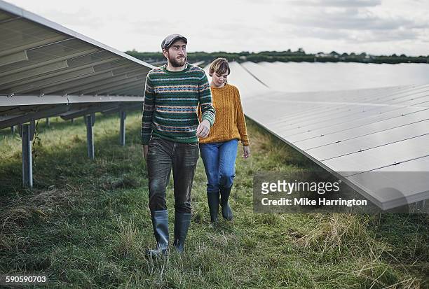 two farmers walking through solar farm - coppia eterosessuale foto e immagini stock