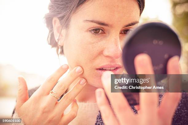 checking my look in powder compact mirror - woman look up stockfoto's en -beelden