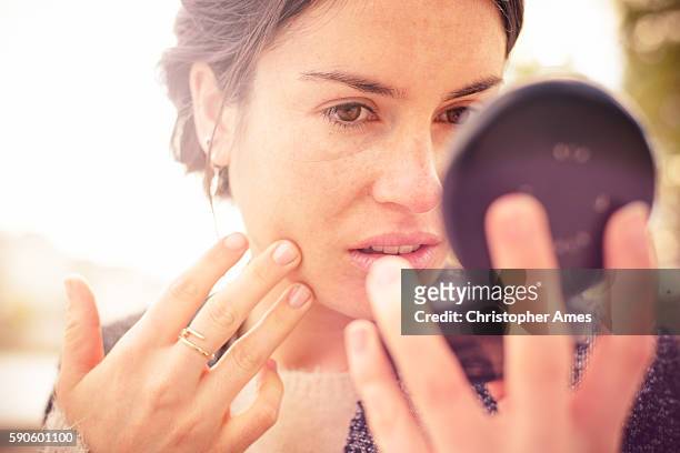 checking my look in powder compact mirror - pele imagens e fotografias de stock