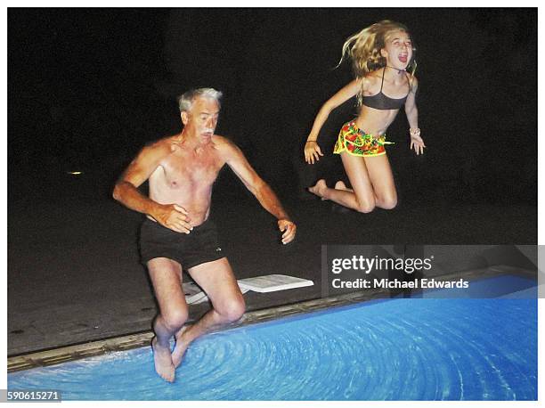 grandfather and granddaughter jumping tinto pool - zwembroek stockfoto's en -beelden