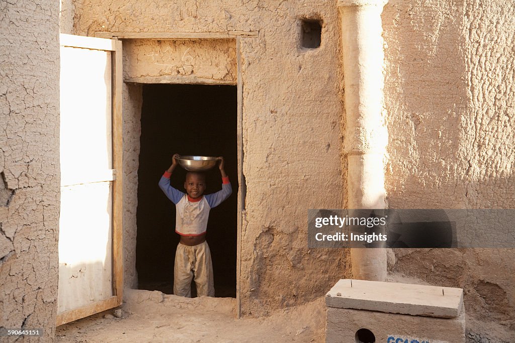 Boy standing with a container on head.