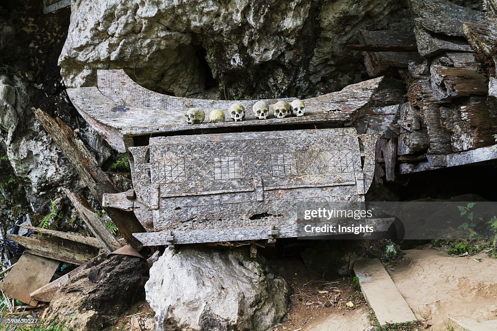 Wooden coffin and skulls on a rocky outcrop.