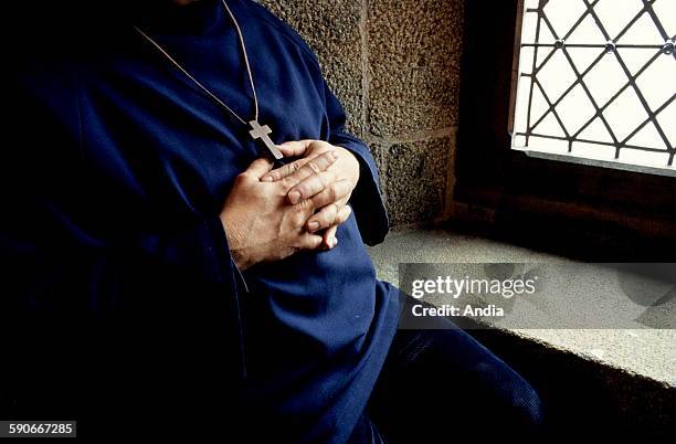 Monk of the abbey of Mont Saint-Michel , seated near a window, his arms folded on his chest with a wooden cross. Meditation; prayer; Spirituality;...