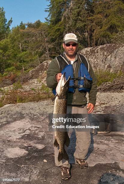 Ontario, Quetico Park, Lake Kawnipi, wilderness, Man with 18 inch Northern Pike.