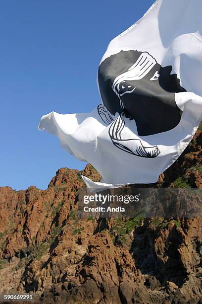 Corsican flag flying in the wind in the Scandola Nature Reserve , in the Haute Corse department