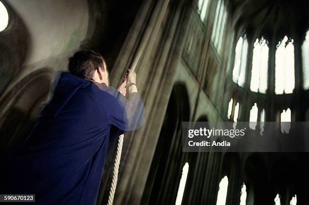 Monk of the abbey of Mont Saint-Michel ringing the church bells thanks to a rope.