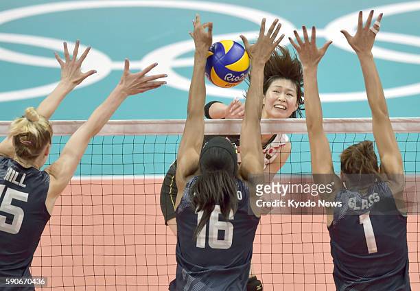 Saori Kimura of Japan has a spike blocked by Foluke Akinradewo of the United States flanked by teammates Kimberly Hill and Alisha Glass during the...