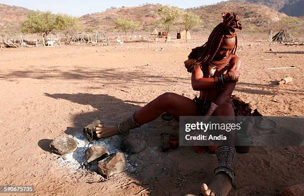 Himba woman anoiting with a clay and sap mixture that Himbas are used to cover themselves with in a beauty concern and to protect themselves, close...