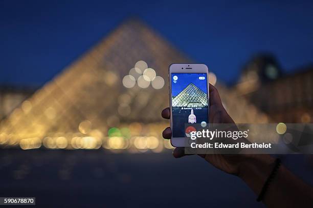 Man launches a Pokeball to catch a Ramoloss character while playing Nintendo Co.'s Pokemon Go augmented-reality game near The Louvre Pyramid, on...