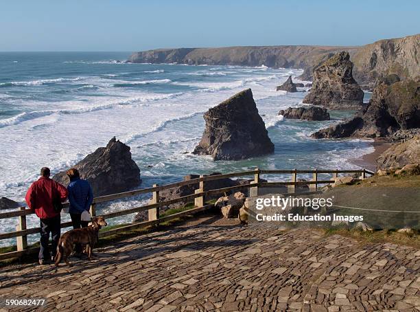 Couple at viewing area looking at Sea stacks at Carnewas known as the Bedruthan Steps, Cornwall, UK.