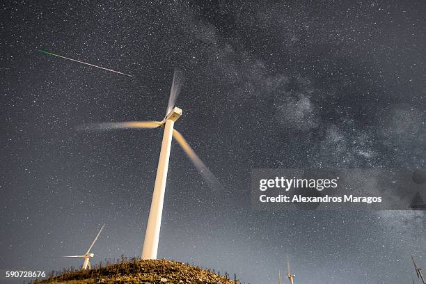 wind turbines at night with the milky way and a meteor - wind turbine long exposure stock-fotos und bilder