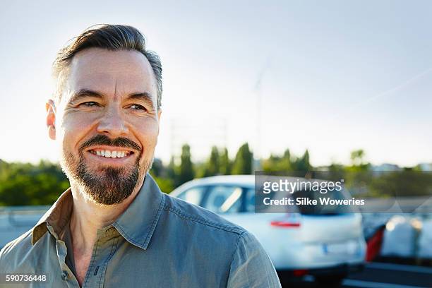 middle-aged man standing beside his car - car salesman stock pictures, royalty-free photos & images