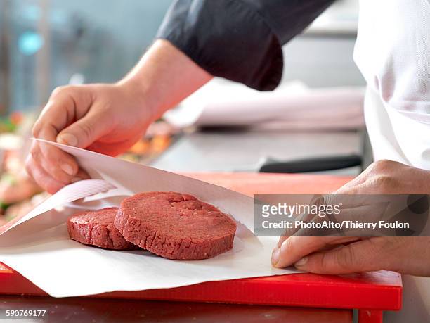 butcher wrapping beef patties in wax paper, cropped - metzger stock-fotos und bilder