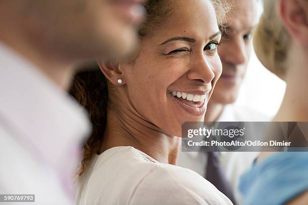 woman with colleagues, winking playfully at camera - zwinkern stock-fotos und bilder