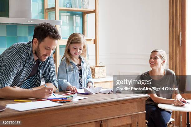 parents spending time with young daughter at home - origami instructions stock pictures, royalty-free photos & images