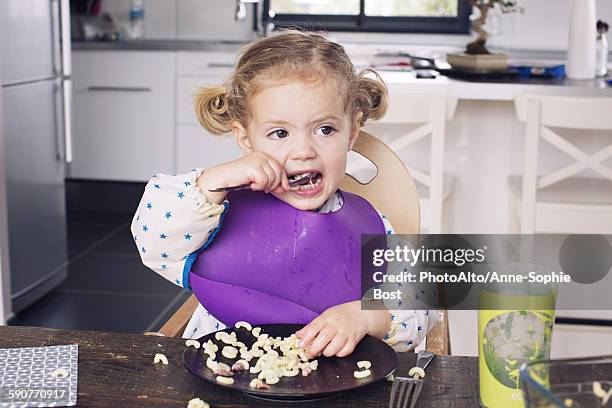 little girl eating lunch - eating with a bib stock pictures, royalty-free photos & images