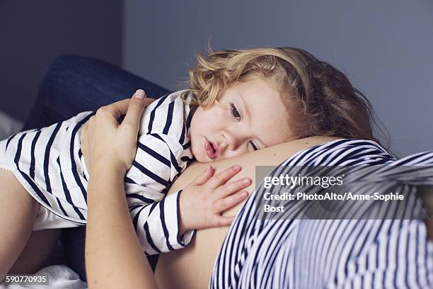 little girl resting her head and hand on mothers pregnant stomach - hände auf bauch stock-fotos und bilder