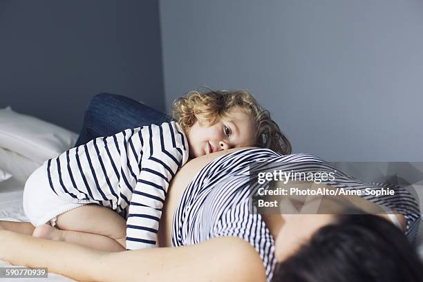 little girl and pregnant mother lying together on bed - anne sophie mutter stock-fotos und bilder